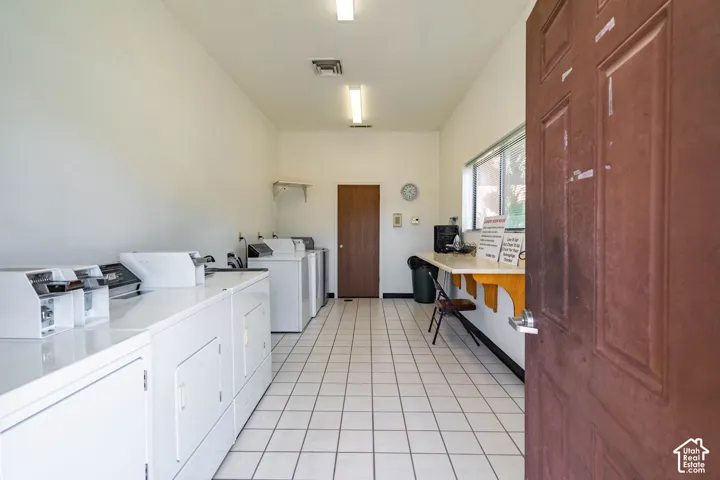 Utility room featuring ceramic tile flooring, built-in counter space, multiple laundry appliance hookups, and fluorescent lighting