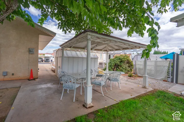 Concrete patio featuring a permanent metal gazebo, metal storage shed, and decorative gravel landscaping