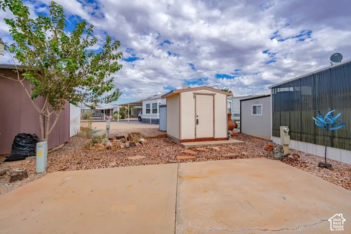 Exterior space featuring a concrete parking pad, detached storage structure with a solid door, and low-maintenance stone landscaping