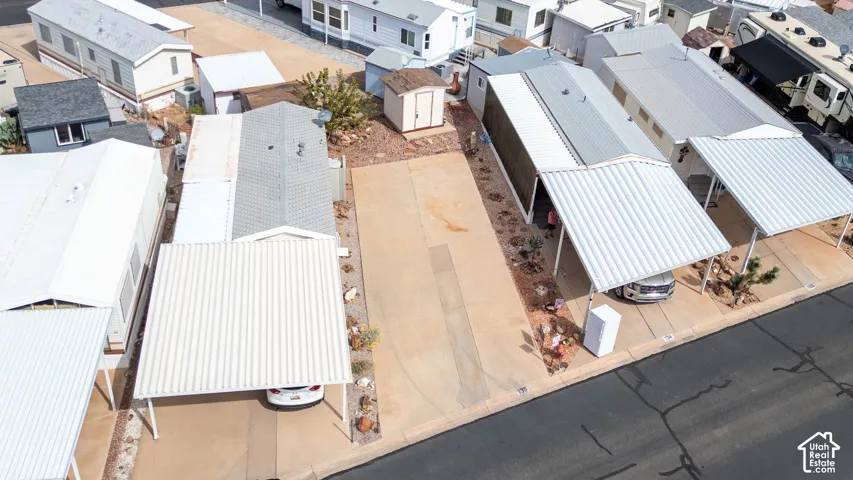Concrete driveway featuring a metal carport and an exterior storage shed