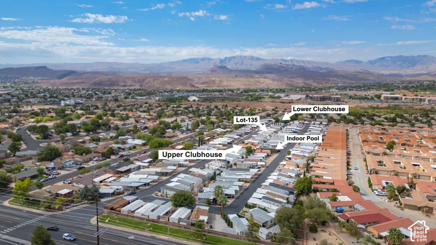 Aerial perspective of the community, highlighting the upper clubhouse, lower clubhouse, indoor pool facility, and lot-135, set against a mountainous backdrop