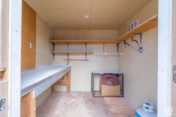 Storage space featuring built-in wood shelving, an integrated wooden workbench, and a wall-mounted pegboard