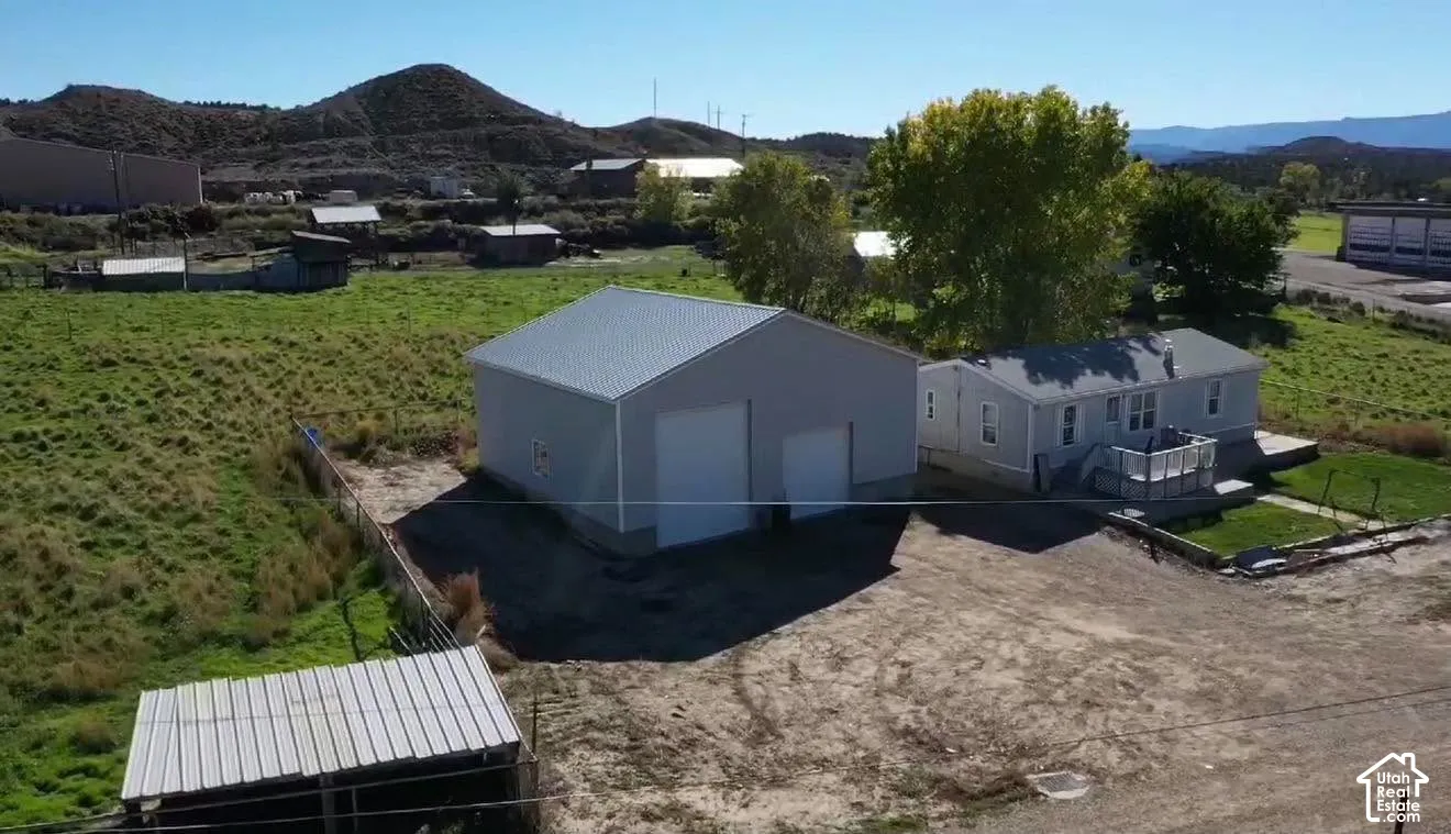 Detached metal-sided workshop featuring dual roll-up doors, metal roof, expansive acreage, and mountain backdrop