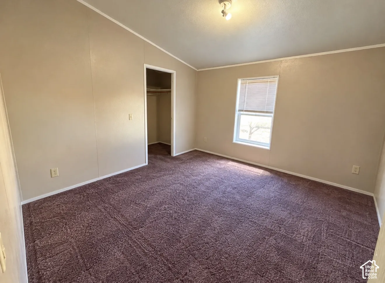 Interior space featuring vaulted ceilings, neutral wall tones, carpeted flooring, and a walk-in closet