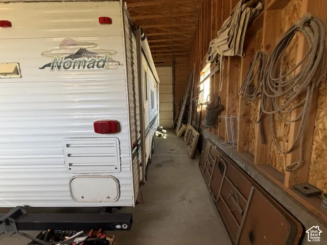 Enclosed storage structure featuring exposed timber framing, concrete flooring, and a roll-up vehicle door