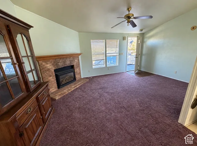 Brick fireplace with a wooden mantel, multiple windows, and a ceiling fan