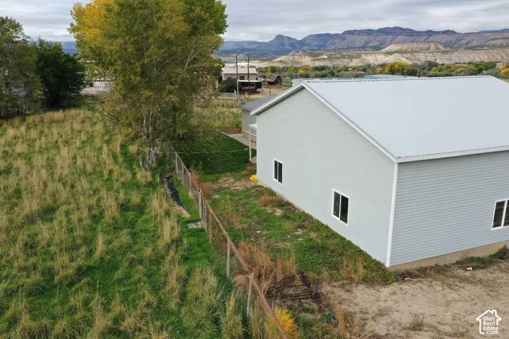 Exterior featuring light-colored horizontal siding, a metal roof, and a fenced perimeter with prominent mountain scenery