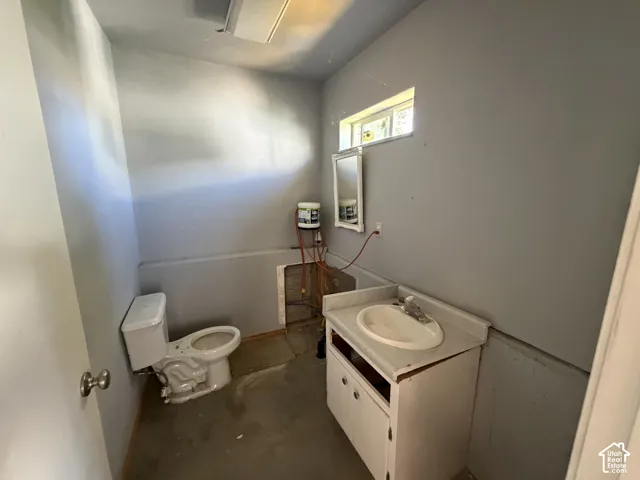 Bathroom featuring a vanity with an integrated basin, a wall-mounted mirror, and a toilet
