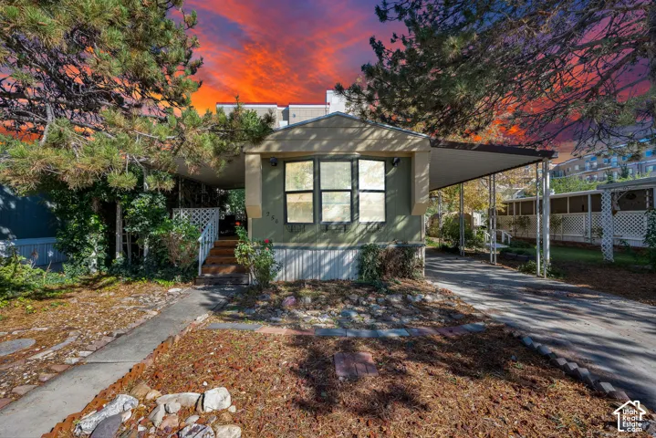 Exterior featuring a covered carport, three-pane bay window, and exterior steps with lattice railing
