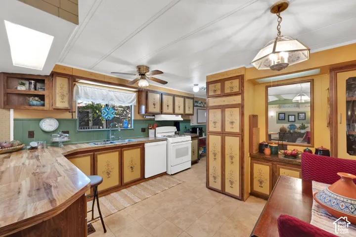Kitchen featuring custom-painted cabinetry, wood-finish countertops, tile flooring, built-in pantry storage, and decorative pendant lighting