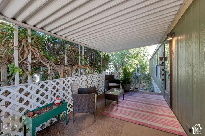 Covered porch featuring a corrugated metal roof, white lattice railing, and vertical wood-texture siding