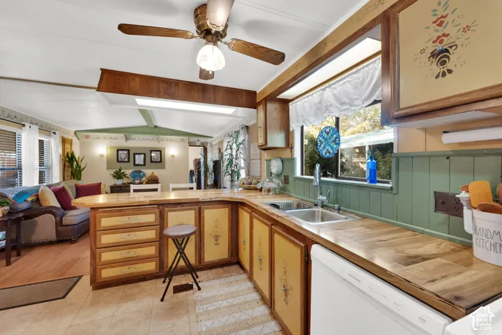 Kitchen featuring wood-finished countertops, painted cabinetry with decorative detailing, an integrated peninsula, a stainless steel dual-basin sink, and a ceiling-mounted fan