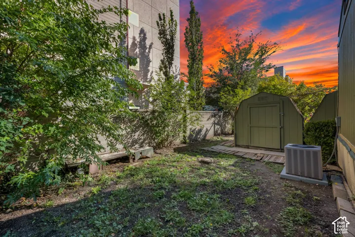 Side yard featuring mature trees, a detached storage shed, and a masonry perimeter wall