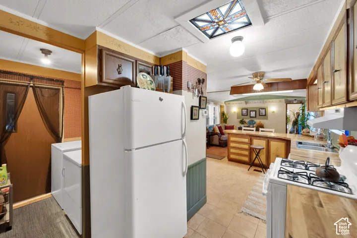 Kitchen featuring wood cabinetry, butcher-block countertops, a decorative stained-glass skylight, and tile flooring