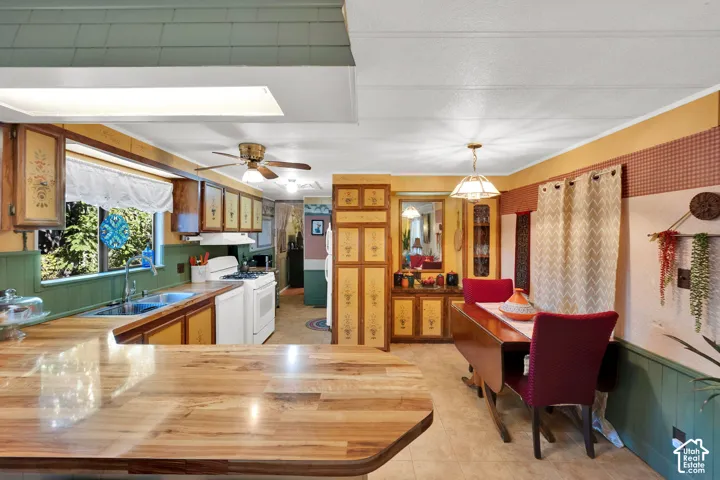 Kitchen featuring a wood-finish peninsula countertop, built-in floor-to-ceiling cabinetry, recessed and pendant lighting, and ceramic tile flooring