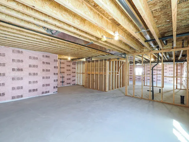 Unfinished lower level featuring exposed wood-joist ceiling, concrete flooring, insulated wall panels, and open wood-stud framing