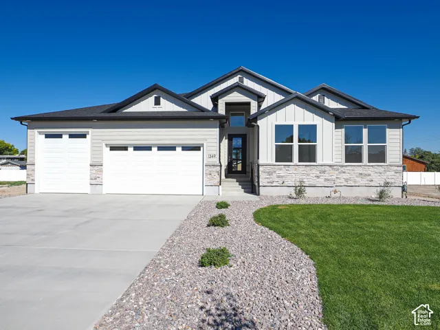 Contemporary exterior featuring horizontal siding, vertical board-and-batten accents, and stone veneer skirting, complemented by a triple-gabled roofline and concrete driveway