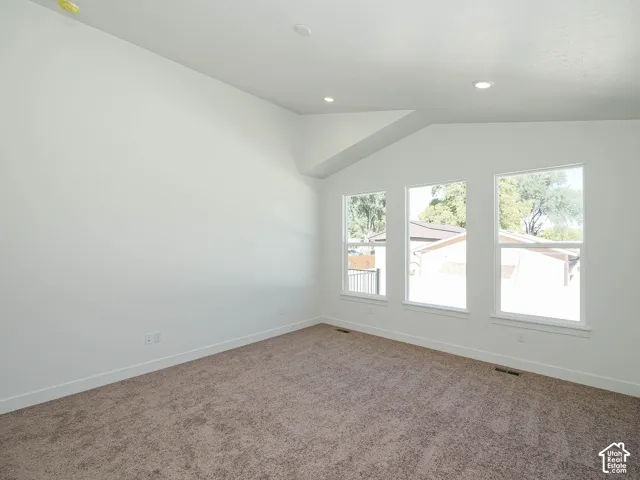 Vaulted ceiling featuring recessed lighting and three windows with neutral carpeting