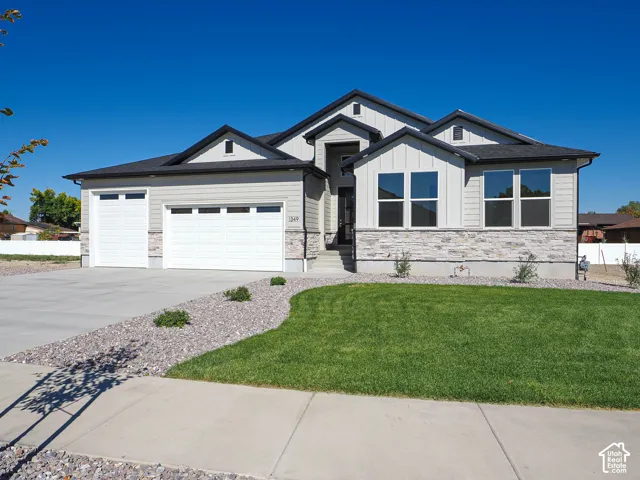 Modern residence featuring a multi-gabled roofline, stone veneer and horizontal siding exterior, three-car garage, and manicured lawn