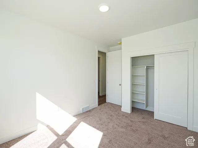Neutral-toned carpeted flooring, sliding-door closet featuring built-in shelving, shaker-style interior doors, and recessed ceiling lighting