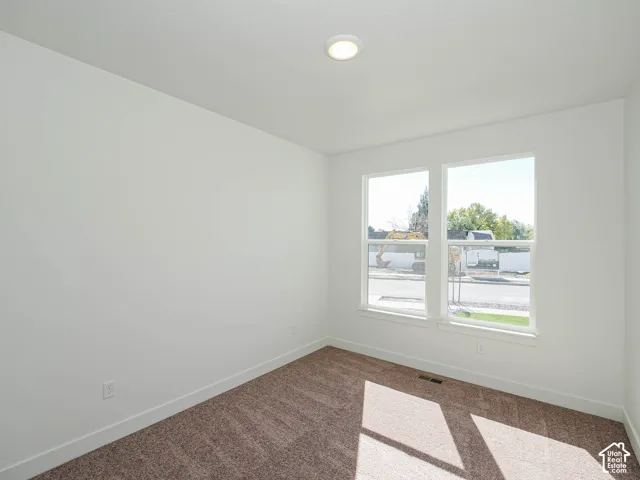 Neutral interior space featuring white walls, textured carpeting, dual-pane windows, and recessed ceiling lighting