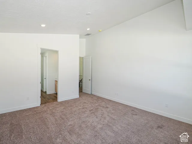 Vaulted ceilings, neutral carpeting, and recessed lighting