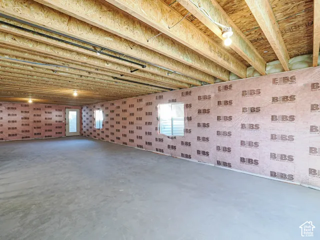 Unfinished lower level featuring concrete flooring, exposed wood joist ceilings, and exterior wall insulation