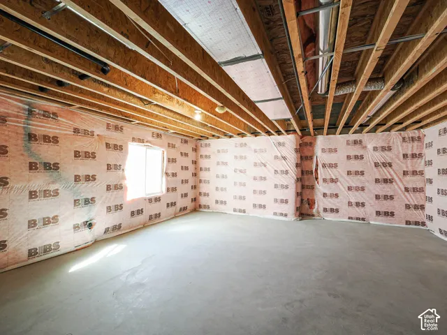 Unfinished interior space featuring exposed wood joist ceiling, concrete slab flooring, insulated wall panels, and a single window