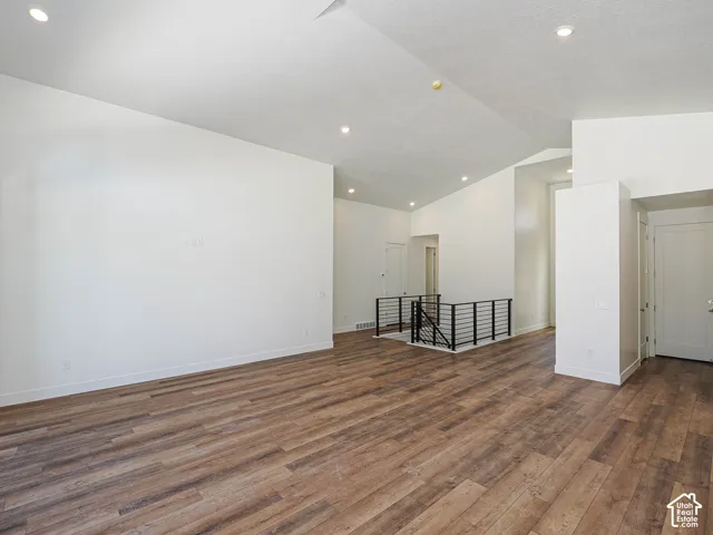 Vaulted ceilings featuring recessed lighting, wood-finish flooring, and a metal stair railing