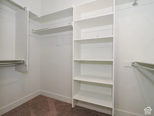 Storage space featuring custom white shelving units and integrated metal clothing rods