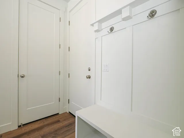 Built-in white storage bench featuring panel detailing, integrated shelving, and metal hardware hooks, complemented by wood-finish flooring and solid-core interior doors