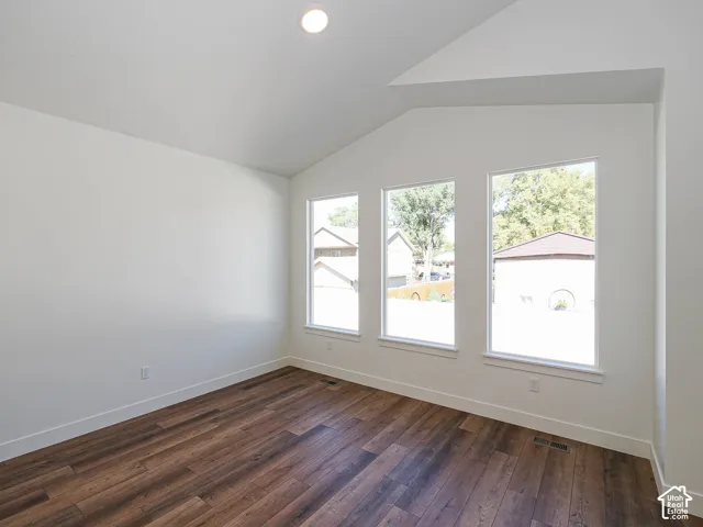 Vaulted ceiling featuring wood-finish flooring, neutral walls, and a trio of large windows