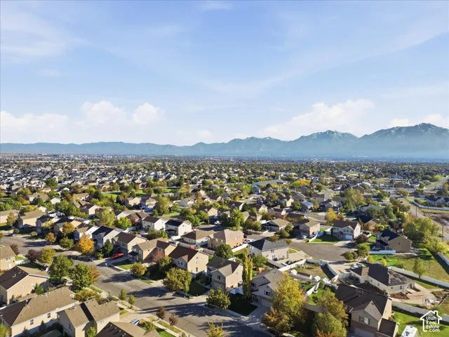 Aerial perspective of a residential neighborhood featuring multi-story dwellings, mature trees, and a mountain backdrop