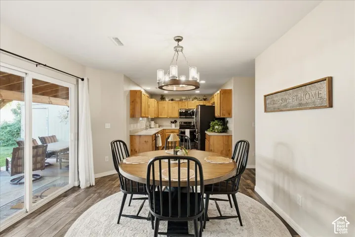 Dining area featuring wood-finish flooring, a wagon-wheel style chandelier, and sliding glass doors