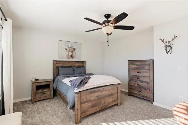 Neutral-toned interior space featuring carpeting and a multi-blade ceiling fan with an integrated light fixture