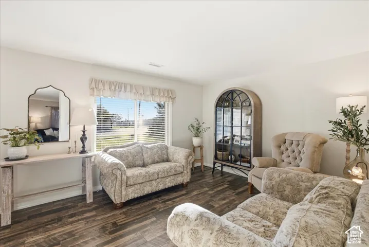 Room interior featuring multi-tonal wood-finish flooring, a large window with horizontal blinds, and a built-in arched display cabinet with metal lattice detailing