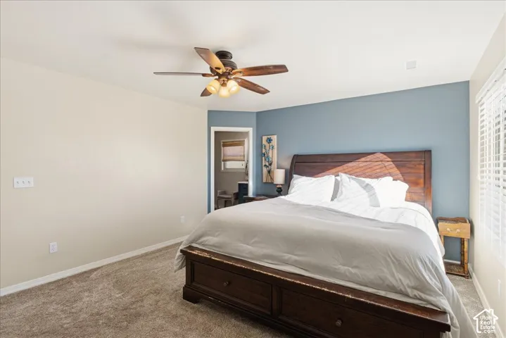 Room featuring neutral-toned carpeting, a blue accent wall, and an integrated ceiling fan with light fixture