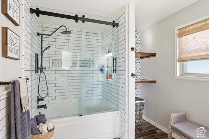 Shower with sliding glass enclosure, white subway tile surround, matte black rainfall showerhead, and built-in recessed shelving