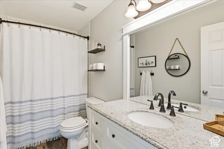 Bathroom featuring a vanity with stone-composite countertop, undermount sink, wide-set matte black faucet, full-width framed mirror, and built-in shelving