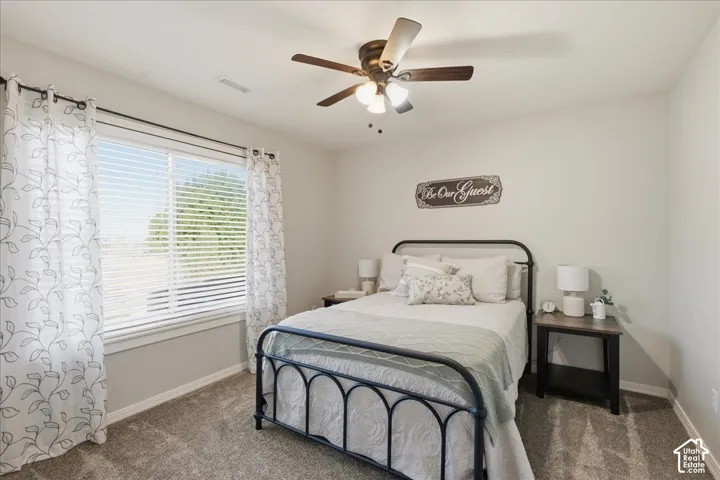 Neutral-toned room featuring wall-to-wall carpeting, a multi-pane window with horizontal blinds, and a central ceiling fan with integrated lighting