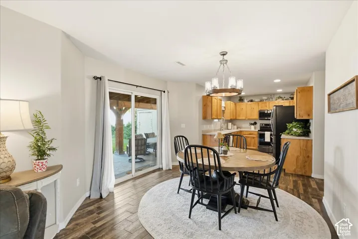 Kitchen featuring wood-finish cabinetry, sliding glass doors to a covered exterior space, wood-finish flooring, and a circular chandelier with integrated lighting