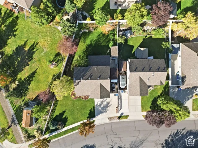 Aerial perspective featuring expansive corner lot, sprawling lawn, mature trees, concrete driveway, and multi-pitched roofline