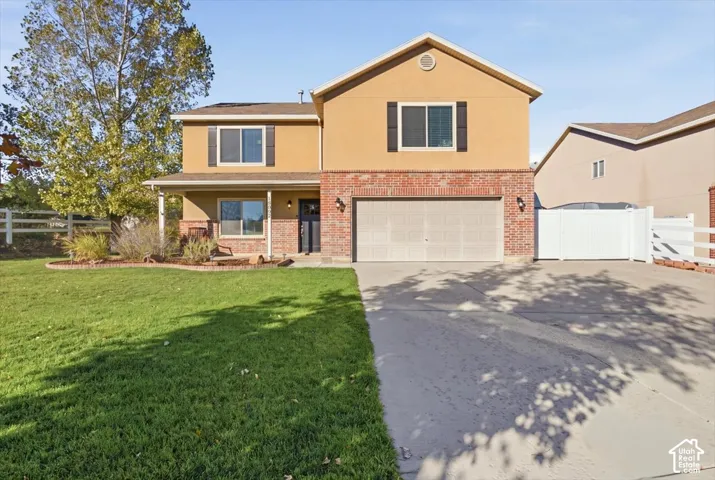 Two-story residence featuring a stucco and brick exterior, an attached two-car garage, and a concrete driveway