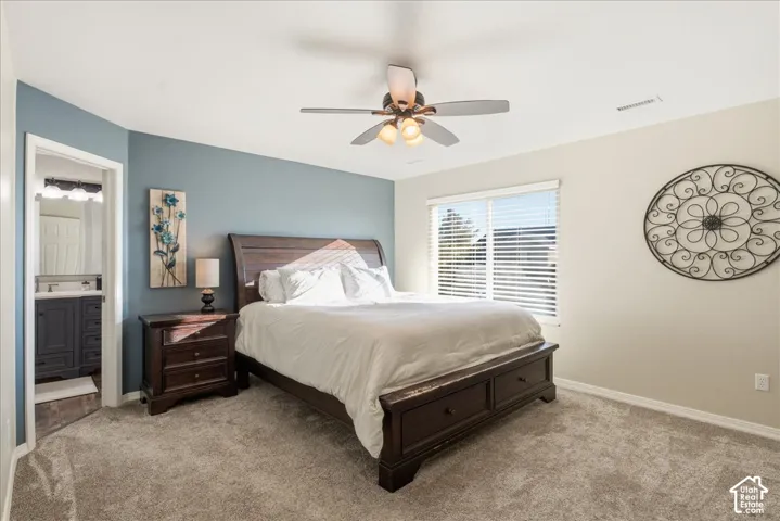 Bedroom featuring an accent wall, neutral carpeting, window with horizontal blinds, and a ceiling fan with integrated lighting