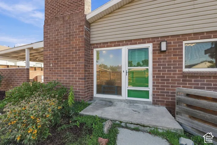 Exterior facade featuring red brick masonry, a prominent chimney, horizontal siding, and a concrete patio