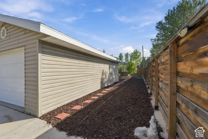 Exterior side yard featuring horizontal siding, a wood fence, and a path of paver stones set in mulch