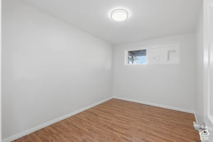 Interior space featuring wood-finish flooring, white walls, flush-mount ceiling lighting, and a rectangular window