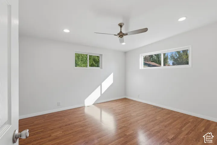Interior space featuring wood-finish flooring, recessed lighting, a multi-blade ceiling fan, and dual sliding windows