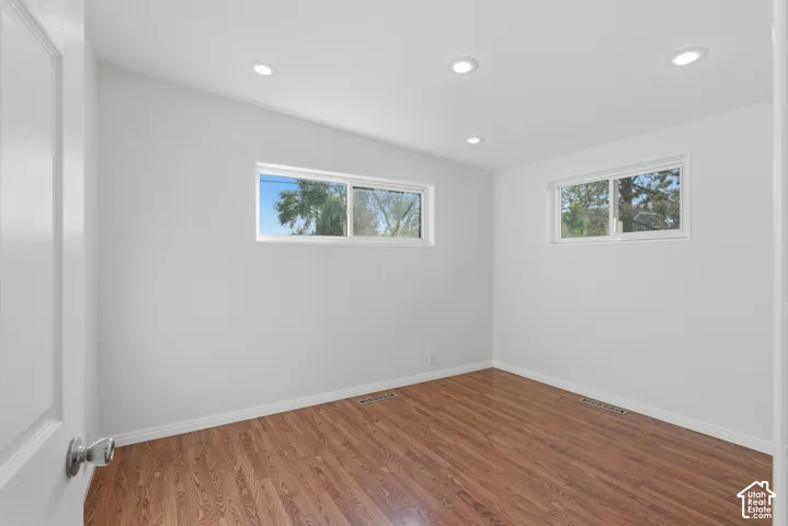 Room featuring wood-finish flooring, recessed lighting, and two sliding windows