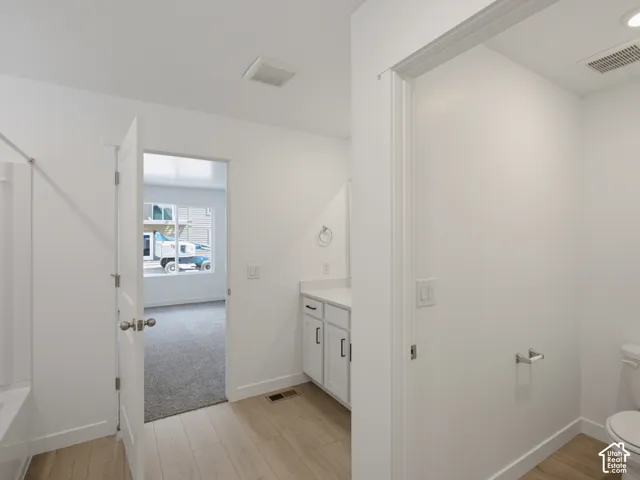 Bathroom featuring white cabinetry, solid surface countertop, wood-finish flooring, and a tub-shower combination